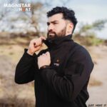 Outdooraufnahme eines Mannes in schwarzer beheizbarer Magnetar Heat Softshelljacke mit hohem Kragen, ideal für kalte Tage.